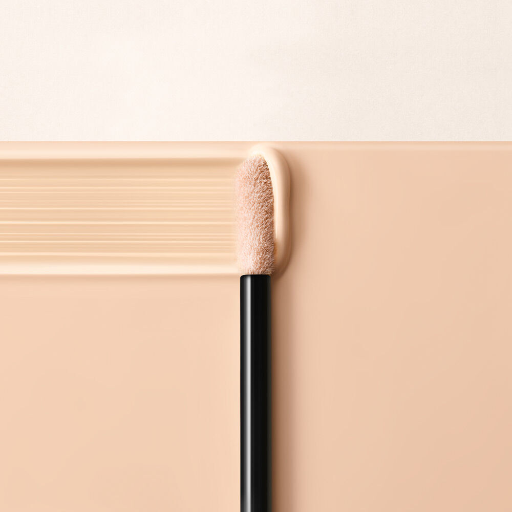 An applicator tip resting on a smooth, creamy beige makeup product, set against a light background.