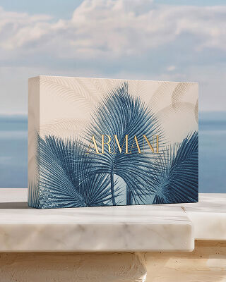 Ein luxurioses Armani Geschenkset mit blauem Botanik-Muster auf Marmor vor dem Meer. Eine Hommage an die „Armani Mare“-Kollektion, die Couture-Handwerkskunst mit sonnendurchfluteter Eleganz und Raffinesse verbindet.