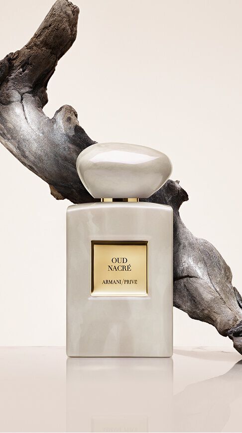 Armani/Prive Oud Nacre: ein Flakon mit perlmuttartigen Reflexen vor einem Stuck Treibholz, der die zeitlose Erhabenheit von Oud in einer Note von absoluter Reinheit und Eleganz einfangt.