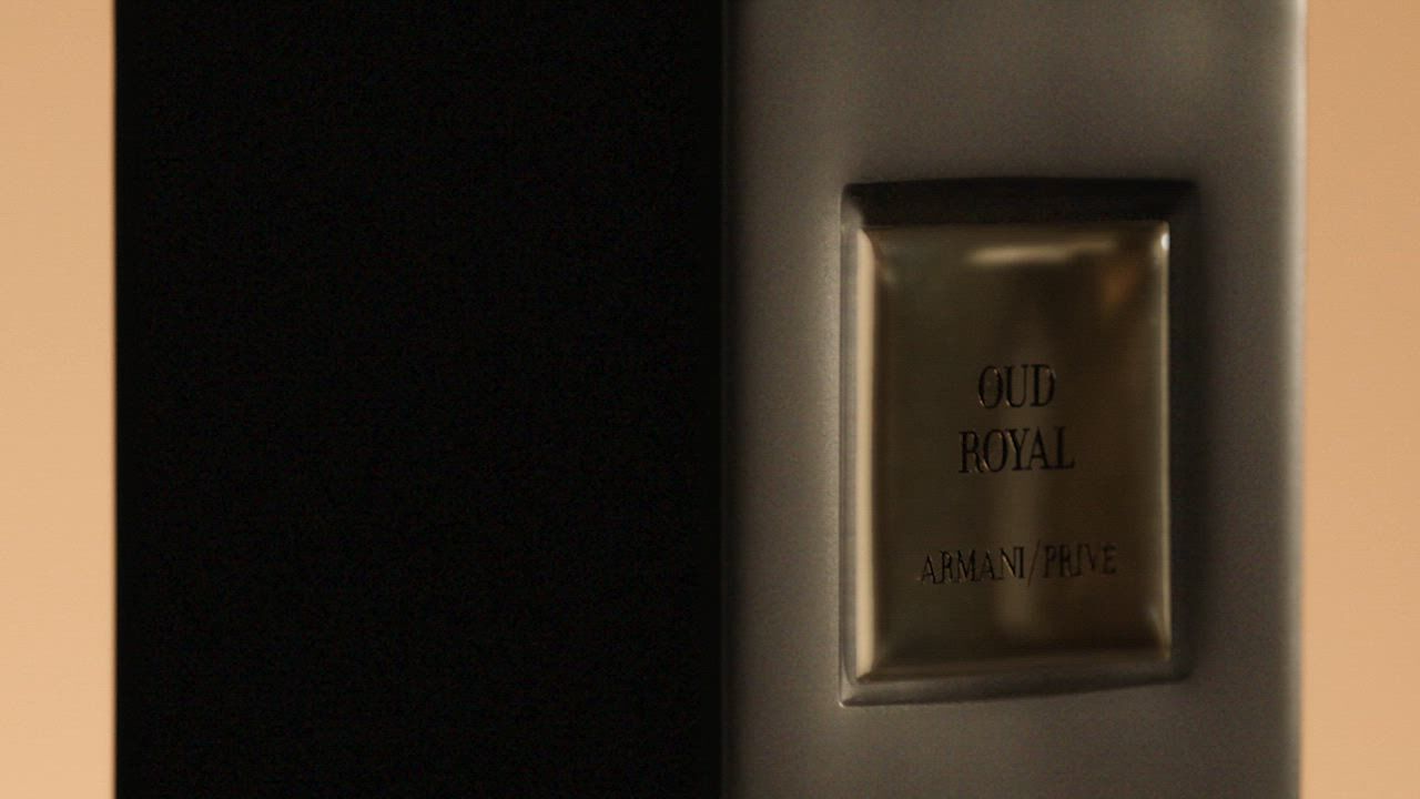 A dark "Armani/Prive OUD ROYAL" fragrance bottle with a black, reflective cap. Overlays of dark, textured wood and a shimmering black flower emphasize the rich, mysterious scent.