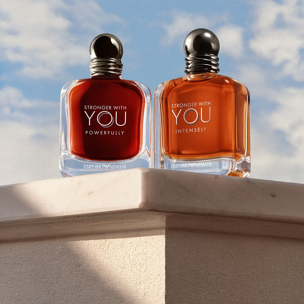 Die Dufte Stronger With You Powerfully und Stronger With You Intensely von Emporio Armani, prasentiert auf einem Steinsockel vor blauem Himmel.​