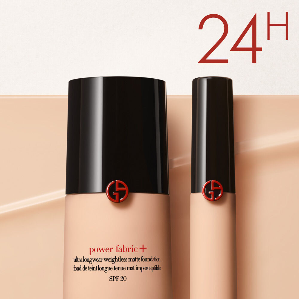 A bottle and a smaller tube of Giorgio Armani's Power Fabric+ ultra longwear matte foundation, featuring a sleek black cap and red logo, against a light beige background. The text "24H" is prominently displayed in the corner.