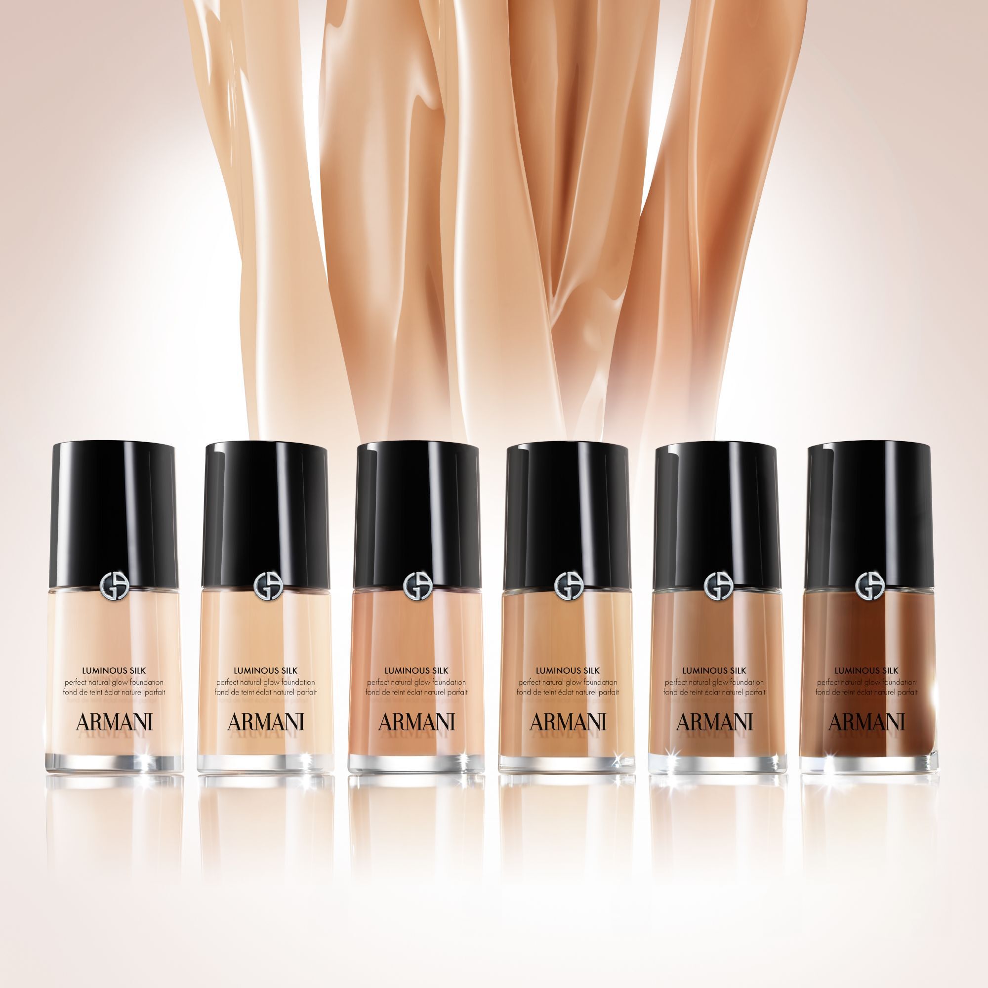 Six bottles of Armani Luminous Silk Foundation arranged in a gradient, displaying a spectrum of shades from very light to deep dark.