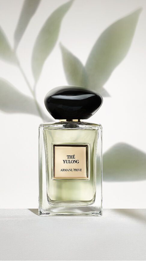 Armani/Prive The Yulong: ein Flakon mit blassgruner Essenz vor einem minimalistischen Hintergrund aus sanften Blatterschatten, der die Gelassenheit von gerauchertem und grunem Tee vereint.